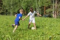 Two boys in uniform plays football on green meadow. Children run and kick soccer ball. Summer children outdoor games Royalty Free Stock Photo