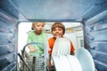 Two boys unload plates from dishwasher inside view