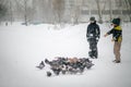 Two boys in winter warm clothes feeds pigeons in city park. Pigeons in snow. Rescue birds in winter from hunger. Care for wild