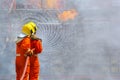 Two brave firefighter using extinguisher and water from hose for fire fighting, Firefighter spraying high pressure water to fire,