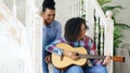 Two brazilian curly girls sistres sitting on stairs and practice to play acoustic guitar. Friends have fun and singing Royalty Free Stock Photo