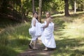 Two brides walk on forest path with skirts in their arms