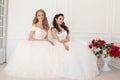 Two brides in wedding dresses sit on a white couch Royalty Free Stock Photo