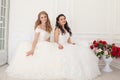 Two brides in wedding dresses sit on a white couch Royalty Free Stock Photo