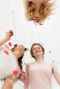 Two bridesmaids having fun with bride. Close-up portrait from below in flying petals. Elegant beige wedding Royalty Free Stock Photo