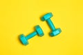 Two bright blue or mint dumbbells are isolated on yellow background. Sport and health concept Royalty Free Stock Photo