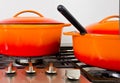 Two bright orange pots from cast iron with enamel at an old vintage gas stove Royalty Free Stock Photo