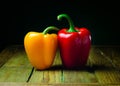 Two bright red bell peppers placed on a rustic wooden table Royalty Free Stock Photo