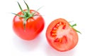 Two bright red and ripe tomatoes lie on the white table. One of them is cut in half. Royalty Free Stock Photo