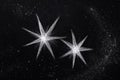 Two bright star-shaped light points shining against a dark, grainy textured background Royalty Free Stock Photo