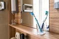 Two bright toothbrushes in glass cup in bathroom with mirror and window in hotel Royalty Free Stock Photo