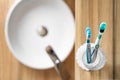 Two bright toothbrushes in glass cup in bathroom near sink and faucet in hotel Royalty Free Stock Photo