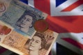 Two British five and ten pound bills and one pound coin on the flag of the United Kingdom Royalty Free Stock Photo