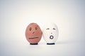 Two broken eggs in the form of human head white and black on a stand complain to each other.