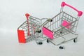 Two broken supermarket trolleys with a falling wheel on a white background. The crisis in the trade. Decline in purchasing power Royalty Free Stock Photo