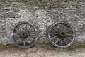 Two broken wooden carrier wheels laying on an old stone mansion house Royalty Free Stock Photo