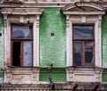 Two broken wooden windows on green brick facade of an old unkempt house Royalty Free Stock Photo