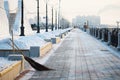 Two brooms. City embankment on a winter morning after snow removal. Flower beds with snowdrifts. Promenade fencing with Royalty Free Stock Photo