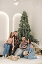 Two brother with their wifes at New Year photosession. Beautiful woman and man in front of fir tree. Christmas mood