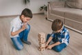 Two brothers boys build a tower of wooden blocks of the house on the floor. Table game. The concept of independent family