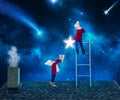 Two brothers in Christmas night standing on the roof of the house and collect the stars from the sky in a bucket.Merry Christmas . Royalty Free Stock Photo