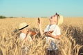 Two brothers eat black round bread on a wheat field.