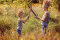 Two Brothers have a crown from dry grass on the head and swords in hands. Joy and play concept.