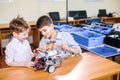 Two brothers kids playing with robot toy at school robotics class, indoor. Royalty Free Stock Photo