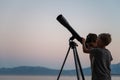 Two brothers looking at the stars using a telescope by the sea Royalty Free Stock Photo