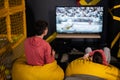 Two brothers playing football video game console, sitting on yellow pouf in kids play center Royalty Free Stock Photo