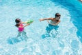 Two brothers playing with a water gun in the pool Royalty Free Stock Photo