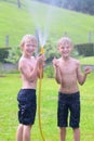 Two brothers playing with water hose in the garden Royalty Free Stock Photo