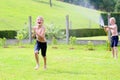 Two brothers playing with water hose in the garden Royalty Free Stock Photo