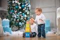 Two brothers playing with wooden alphabet blocks against Christmas tree