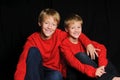 Two brothers in red shirt on black background.