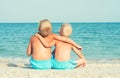 Two brothers relaxing on the beach,sitting on the sand and looking at the sea. Summer vacations.