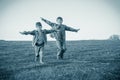 Two brothers running together on meadow, sepia toned Royalty Free Stock Photo