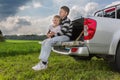 Two brothers siiting on a car trunk on natural