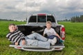 Two brothers siiting on a car trunk