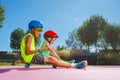Two brothers sit on the skate riding together in helmets Royalty Free Stock Photo