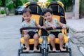 Two brothers sit in a stroller. Adorable twin baby boys sitting in stroller and smiling happily. Childhood emotions.