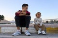 Two brothers sitting outside on a sidewalk and have fun.