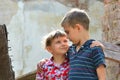 Two brothers stand near the ruined house, the concept of natural disaster, fire, and devastation.