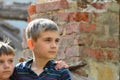 Two brothers stand near the ruined house, the concept of natural disaster, fire, and devastation. Royalty Free Stock Photo