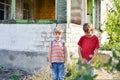 Two brothers are standing near a burned-out house, who lost their homes as a result of hostilities and natural disasters Royalty Free Stock Photo