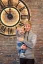 Two brothers teenager and toddler indors near a huge clock 5 minutes before midnight christmas