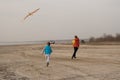 Two brothers 10 and 4 years old play on an empty beach. Flying a kite Royalty Free Stock Photo