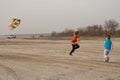 Two brothers 10 and 4 years old play on an empty beach. Flying a kite Royalty Free Stock Photo