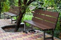 Two brown benches standing on a tile of yellow-red color