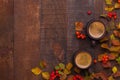 Two brown clay cups of black coffee and branches of autumn leaves Spiraea Vanhouttei with small red rowan`s fruits on the old wo